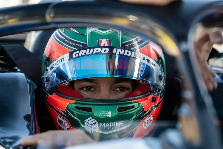 Close-up of a race car driver wearing a colorful helmet with sponsor logos, sitting inside a race car.
