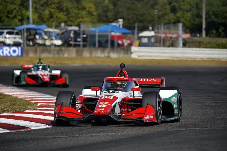 IndyCar drivers race wheel-to-wheel through a circuit corner