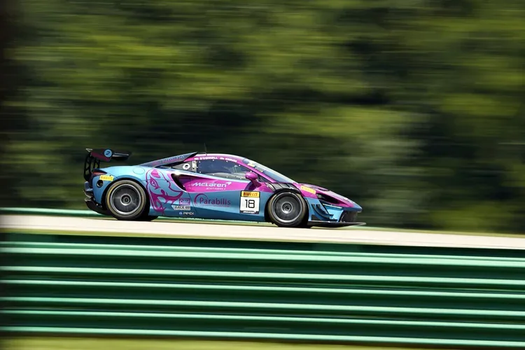 Colorful race car speeding on a track with a blur background of trees, showing motion and speed.