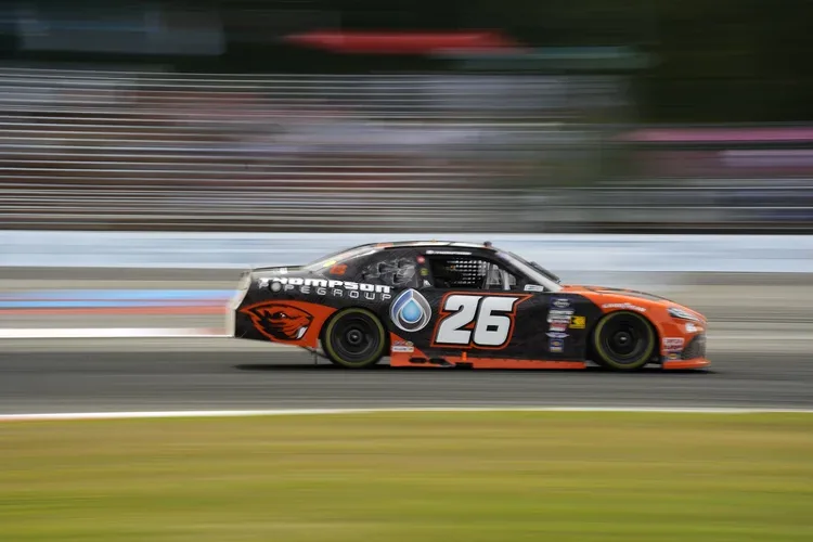 Race car with orange and black livery speeding on a track