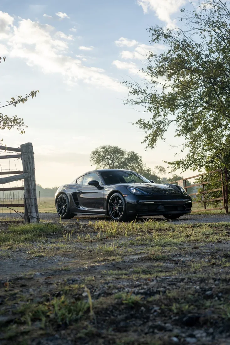 A black sports car parked on a country road during late afternoon or early evening.