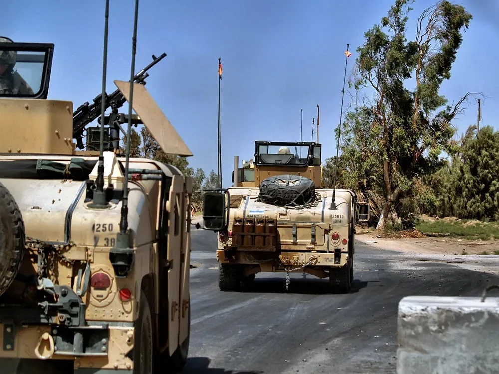 Military vehicles traveling along a road in a convoy