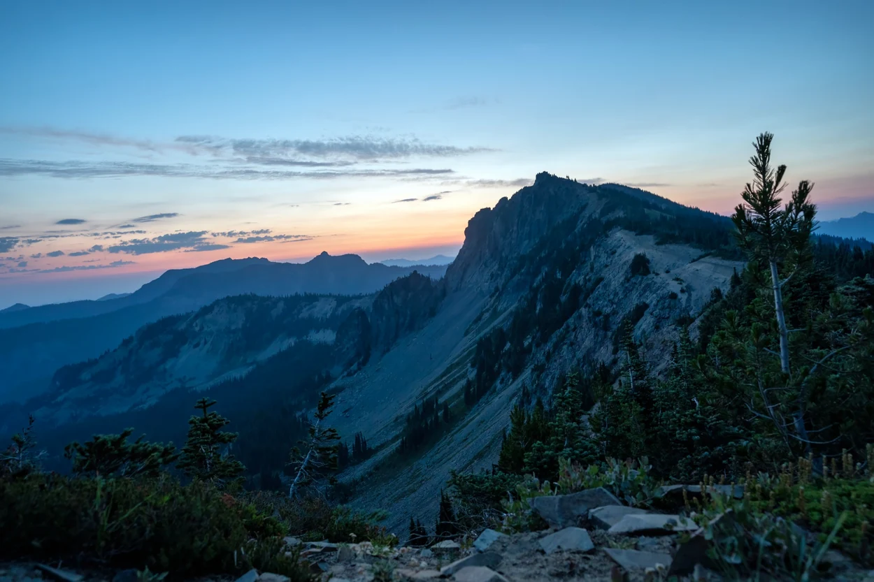 Rocky ridgeline and distant mountains under a pastel sunset sky