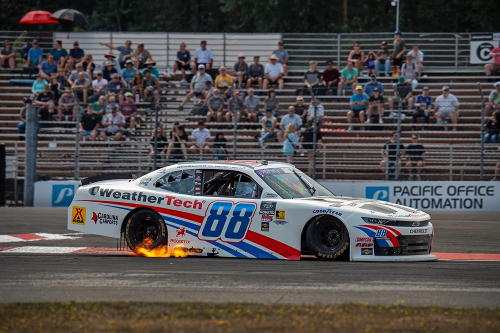 WeatherTech number 88 NASCAR Xfinity Series race car throwing sparks and flames on track